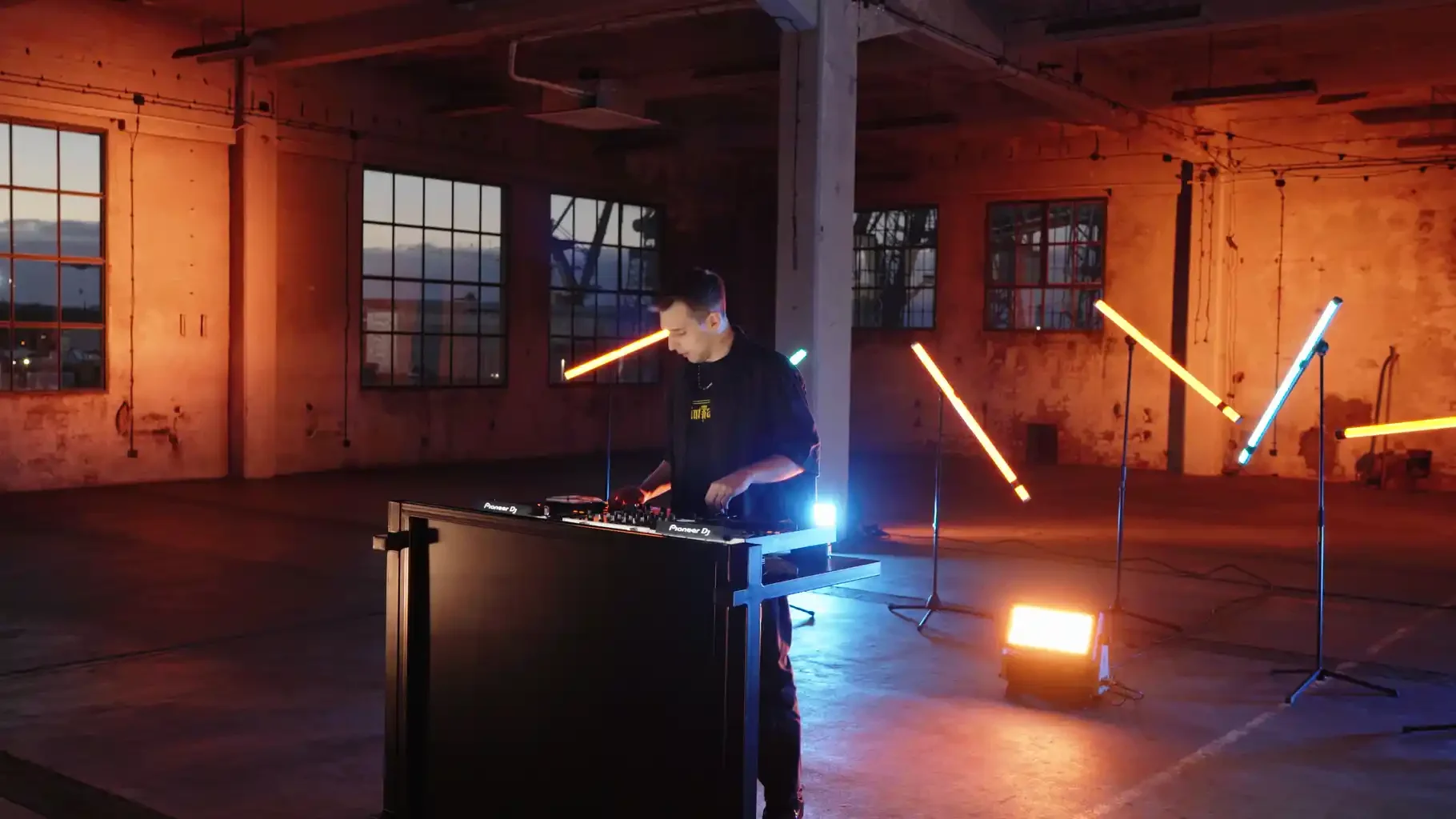 DJ in an industrial hall surrounded by warm and cool LED lighting